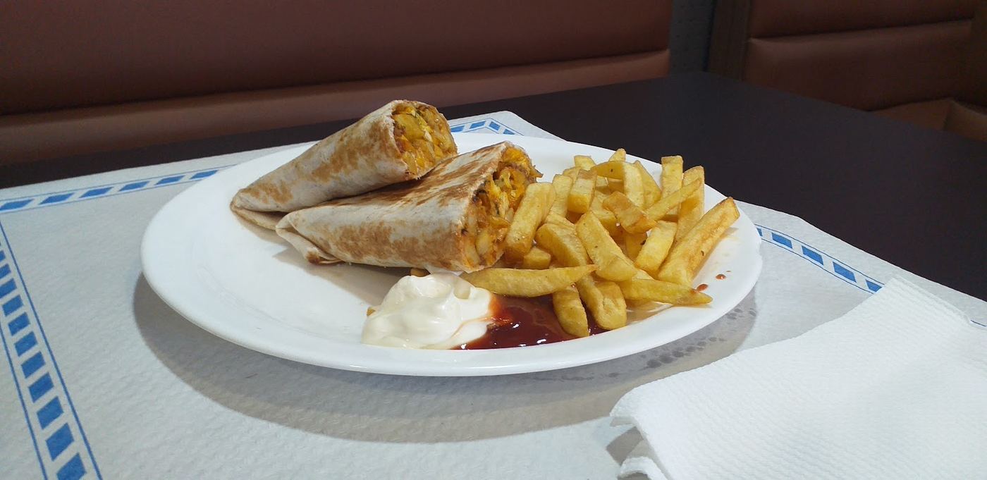 Wrap de pollo especiado acompañado de patatas fritas.